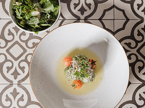 Gourmet-Spinatknödel in Brühe mit Cherrytomaten und Microgreens, dazu frischer grüner Salat